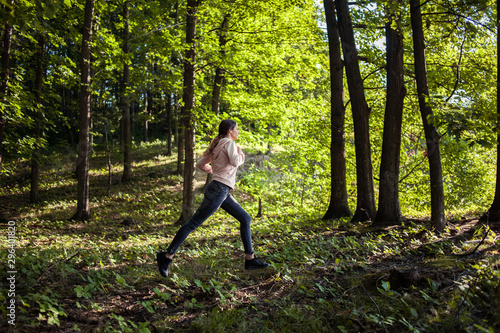 Young girl jogging in the woods on a sunny morning. © xpabli