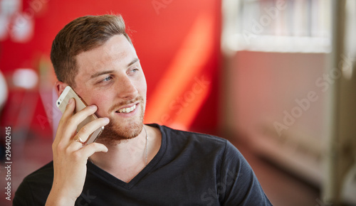 Confident male designer talking on a mobile phone in red creativ