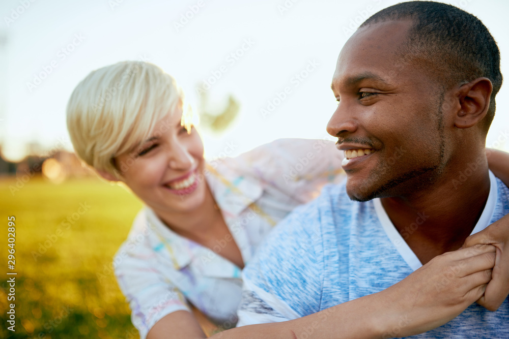 Mixed race couple of millennial in a grass field embracing for a Mixed race couple of millennial in a grass field embracing for a