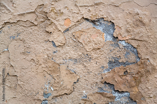 old beige gray heavily damaged concrete wall with cracks and peeling paint. rough surface texture