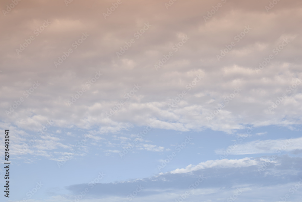 The clouds. The light of the sun through the clouds against a bright sky at sunset. Clouds on the blue sky. Sunset.