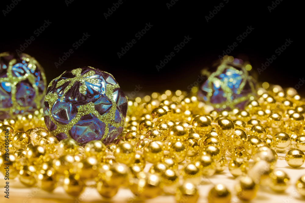 Christmas toys with the beads on the table a black background. Gold beads with blue balls. Christmas decorations with shiny patterns. Christmas toys with the beads on the table a black background. Gold beads with blue balls. Christmas decorations with shiny patterns.