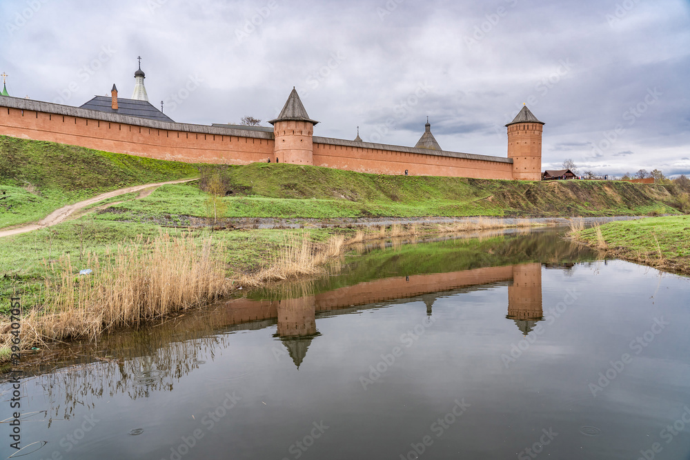 Naklejka premium Walls and towers of Spaso-Evfimiev (Saint Euthymius) Monastery with reflection in Kamenka river in Suzdal, a well preserved old Russian town-museum. A member of the Golden ring of Russia
