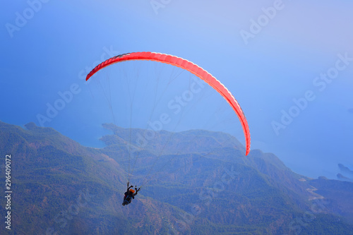 Paragliding. Paraglider flying in the sky over the mountains.Paragliding on the blue sky and sea background.