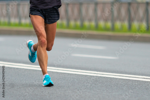 The legs of the athlete. A woman runs along the city road. Muscle work. Close-up