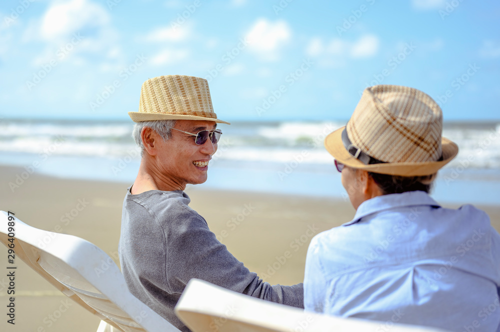 Senior couple sitting on chairs at the beach looking at the ocean on a good day and talking for to plan life insurance at retirement concept.
