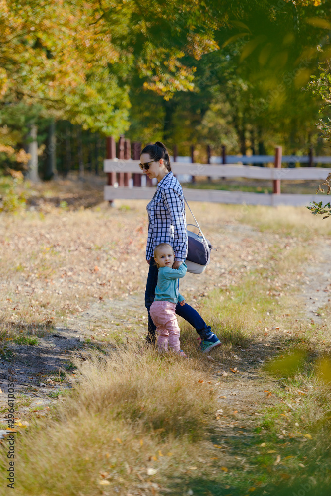 Fototapeta premium Happy mother and daughter in the park. Beauty nature scene with family outdoor lifestyle. Happy family resting together on the green grass, having fun outdoor. Happiness and harmony in family life