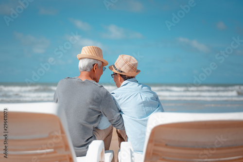 Senior couple sitting on chairs at the beach looking at the ocean on a good day and talking for to plan life insurance at retirement concept. © Day Of Victory Stu.
