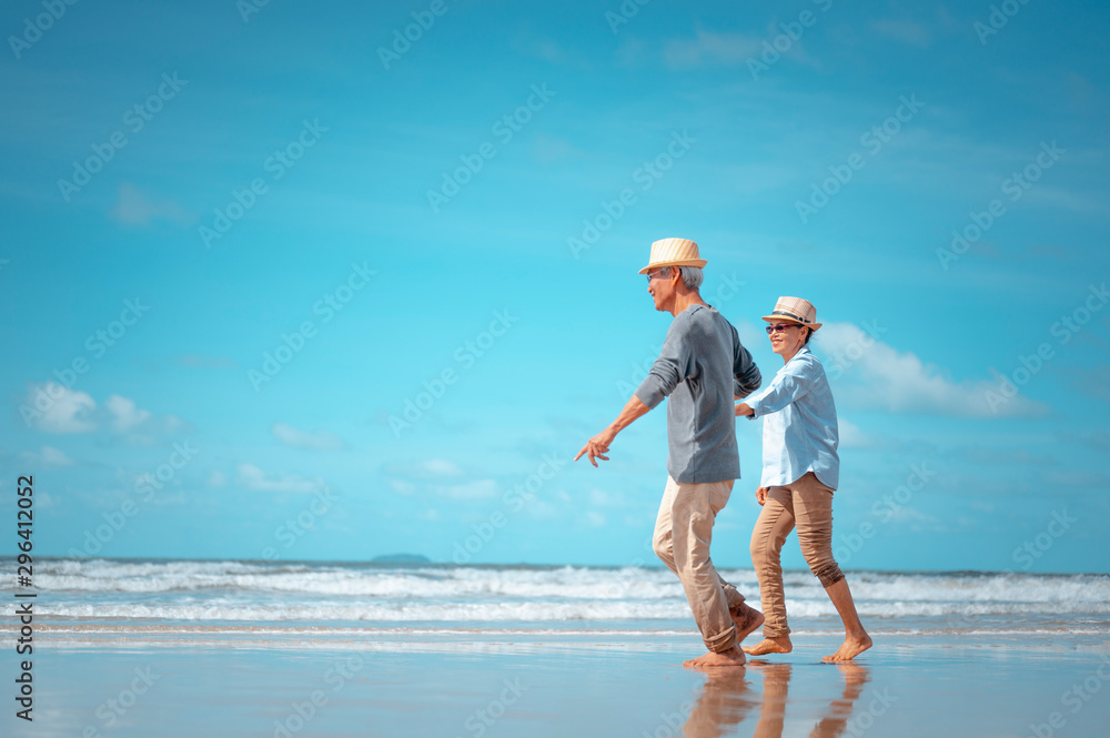 Senior couples walking hand in hand on the beach at sunny day, plan life insurance with the concept of happy retirement. Senior couples walking hand in hand on the beach at sunny day, plan life insurance with the concept of happy retirement.