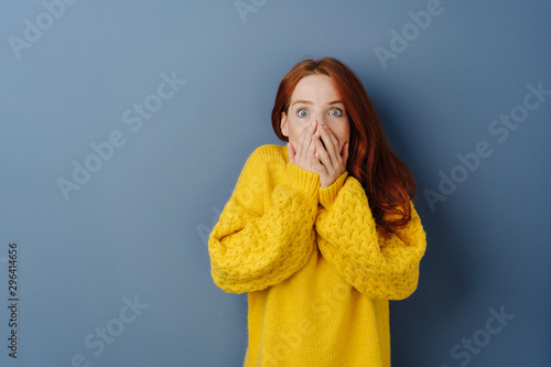Shocked young woman with hands to mouth photo