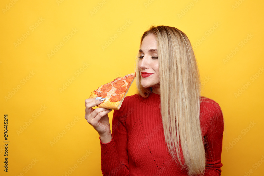 Attractive woman with slice of pizza isolated over the yellow background Attractive woman with slice of pizza isolated over the yellow background