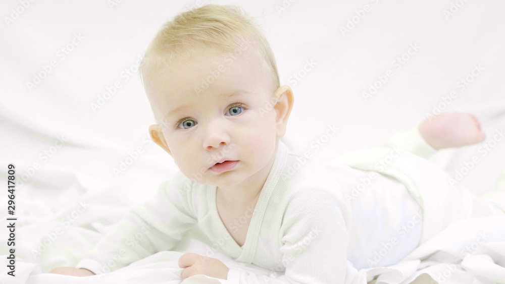 Blond baby with blue eyes lye on bed and look at camera, hypnotize look Blond baby with blue eyes lye on bed and look at camera, hypnotize look