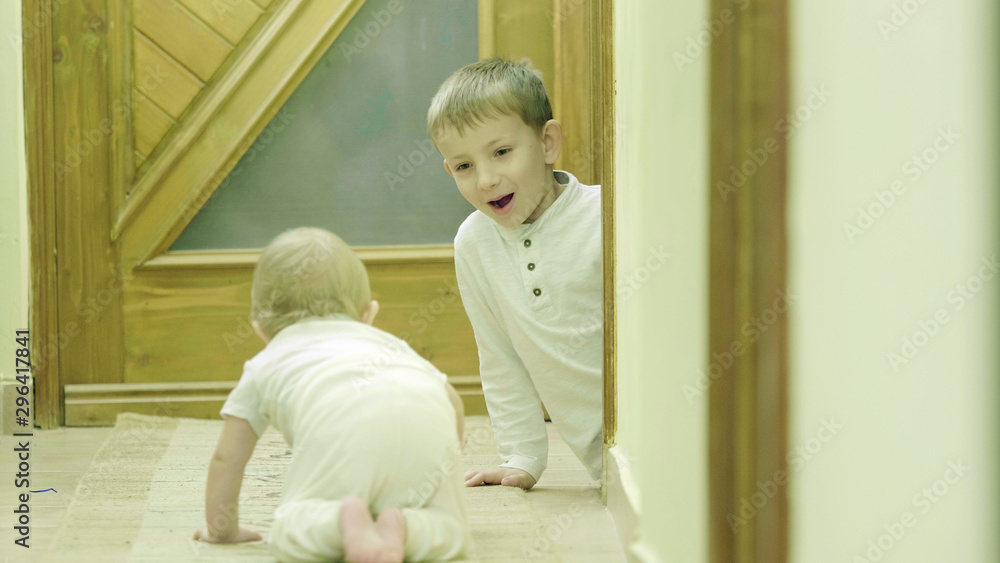 Baby crawling to his brother, children playing hide and seek indoor Baby crawling to his brother, children playing hide and seek indoor