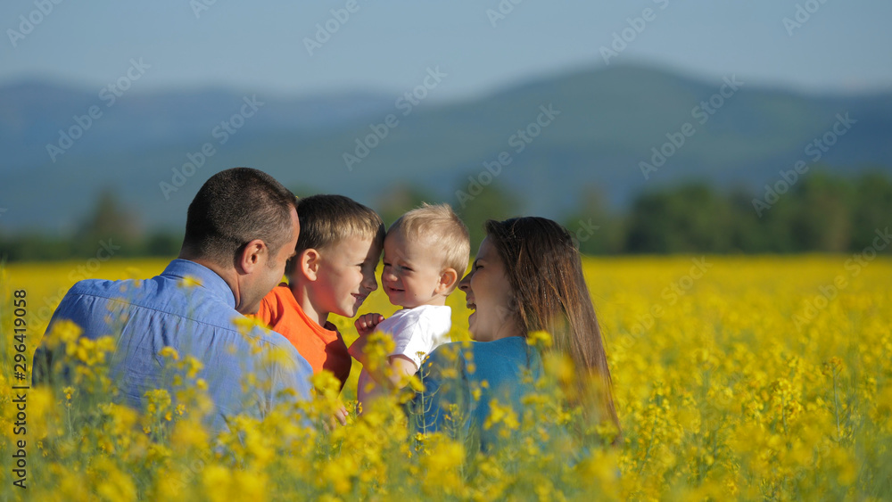 Father holding baby and bigger son in his arms, portrait in blossom rape field Father holding baby and bigger son in his arms, portrait in blossom rape field