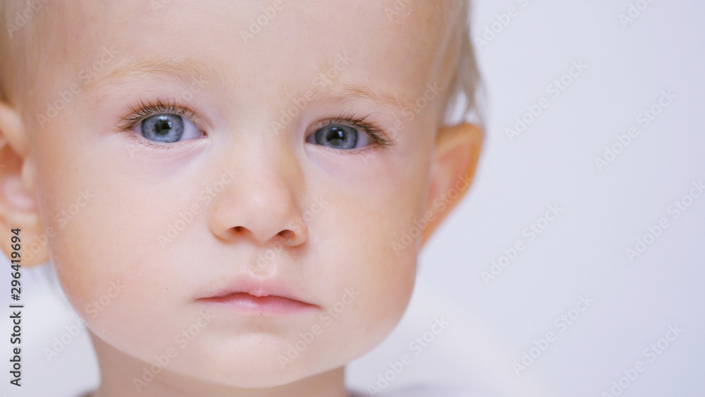 Serious baby portrait, blond child with blue eyes