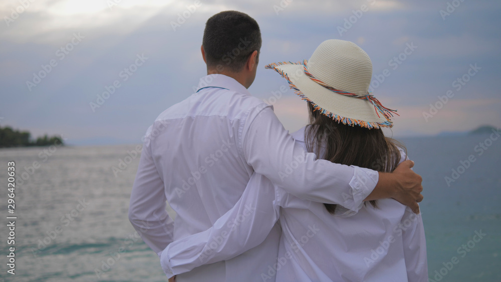 Romantic couple with back embracing, man and woman admire the sea,