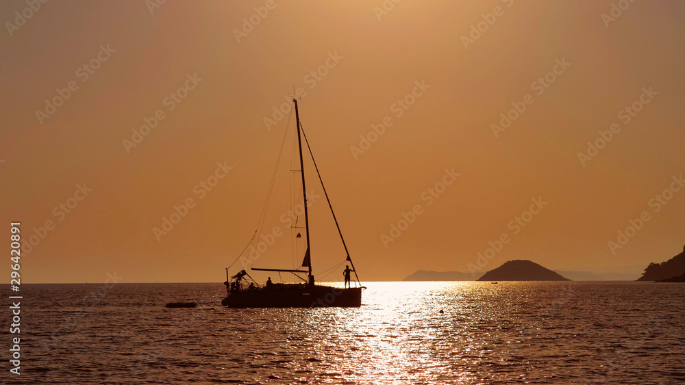 Isolated boat silhouettes go slowly on sea water, beautiful sunset