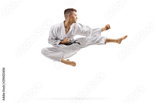 Young man in karate kimono jumping and kicking photo