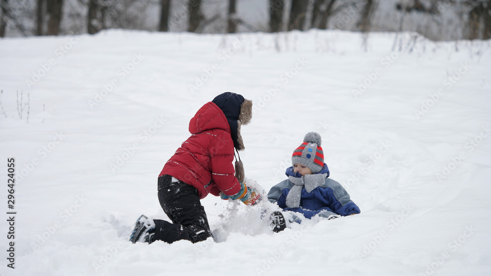 Little kid and big brother play in the snow