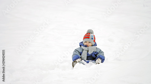 Baby child sitting on snow, isolated boy in white nature