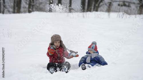 Children sitting and playing with snow, happy childhood in nature