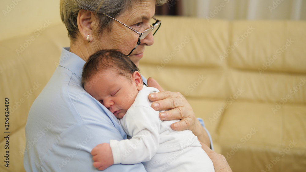Portrait baby sleeping in grandmother arms, family different generations