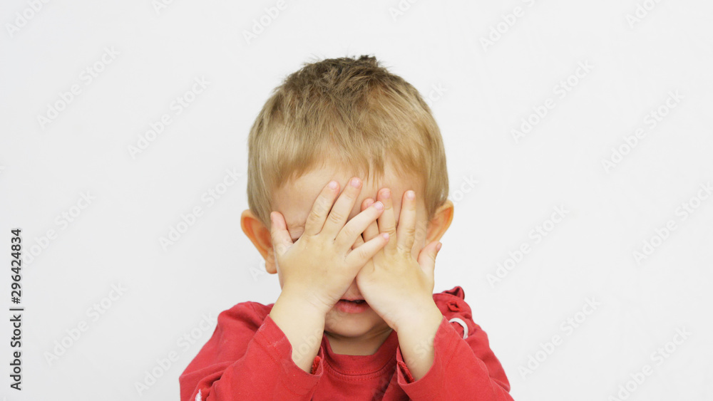 Funny blond child covering his blue eyes with little hands, playful kid Funny blond child covering his blue eyes with little hands, playful kid