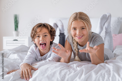 Schooler age brother and sister lying in bed and having fun at the morning