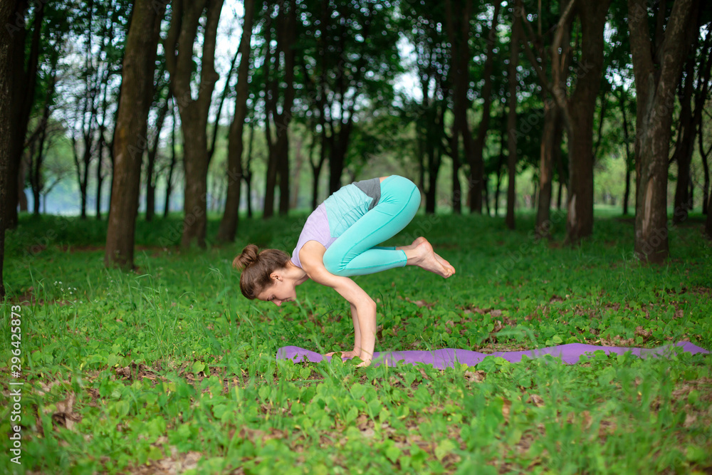 A young sports girl practices yoga in a quit green summer forest, yoga assans posture. Meditation and unity with nature A young sports girl practices yoga in a quit green summer forest, yoga assans posture. Meditation and unity with nature