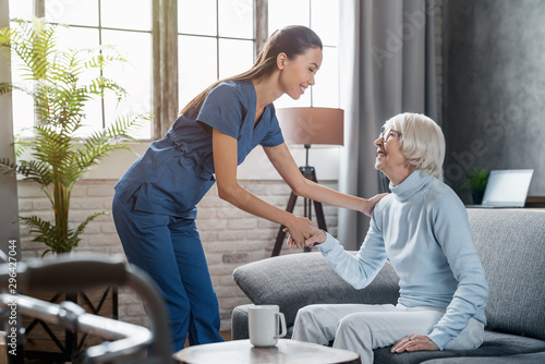 Happy female professional caregiver taking care of elderly woman at home photo