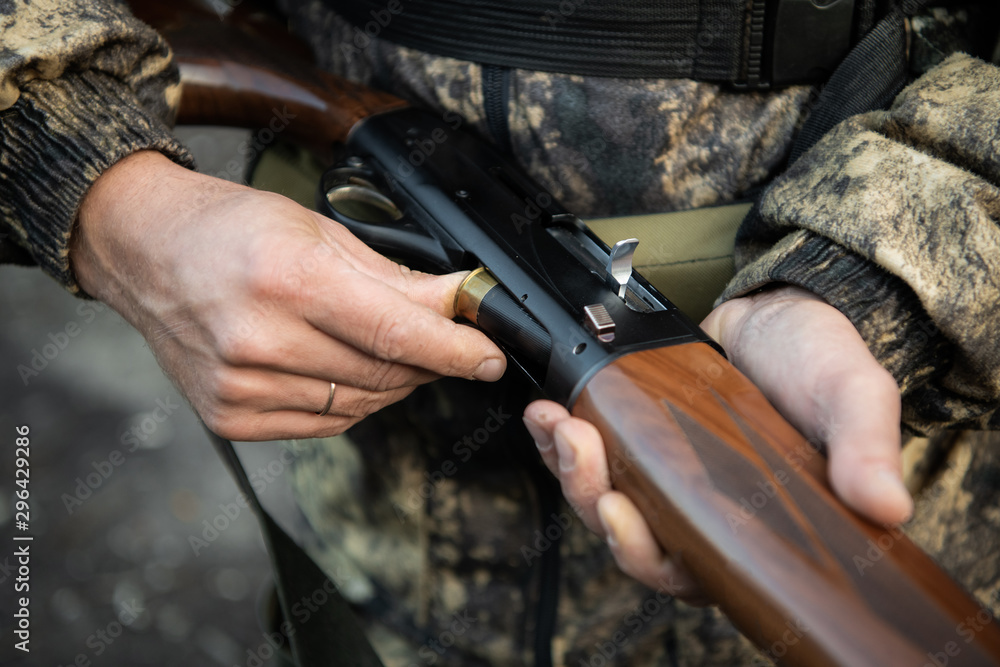 Fototapeta premium Close-up of a hunter hands loading his shotgun