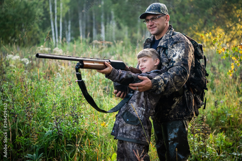 Father teaching his son about gun safety and proper use on hunting in nature.