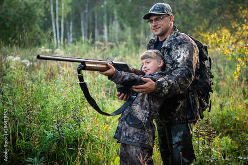 Father teaching his son about gun safety and proper use on hunting in nature.