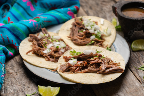 Mexican slow cooked lamb tacos also called barbacoa on wooden background photo