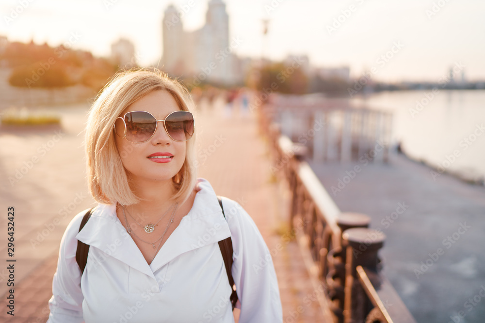 Outdoor portrait of happy young woman on city promenade.