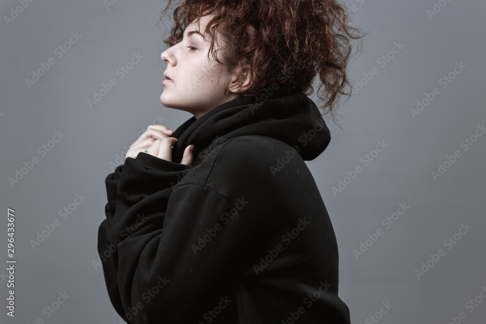 Portrait of a beautiful curly-haired girl with redheads on a gray background Portrait of a beautiful curly-haired girl with redheads on a gray background