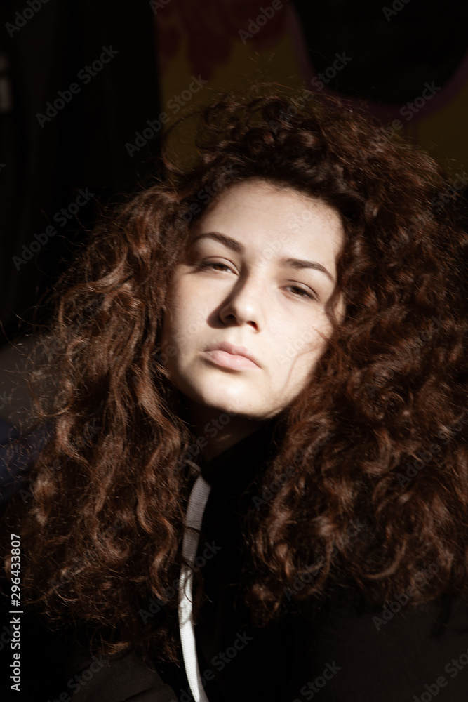 Portrait of a beautiful curly-haired girl with redheads on a gray background