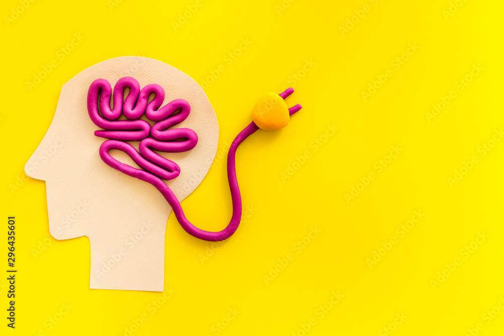 Brain charging and mental rest. Plug and cable leads to plastiline meanders on yellow background top view copy space - obrazy, fototapety, plakaty 