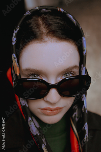 Stylish large portraits of a girl in glasses and a scarf in a studio on a canvas background