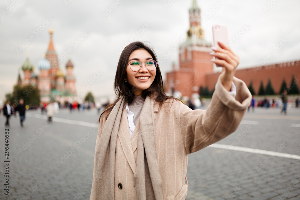 Beautiful business woman of Asian appearance takes a selfie on red square in Moscow