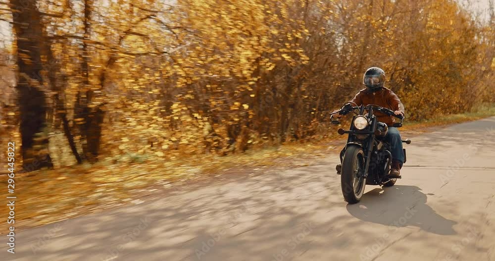 Cool biker rides on the highway in the fall. Motorcyclist walk in a helmet. Cool biker rides on the highway in the fall. Motorcyclist walk in a helmet.