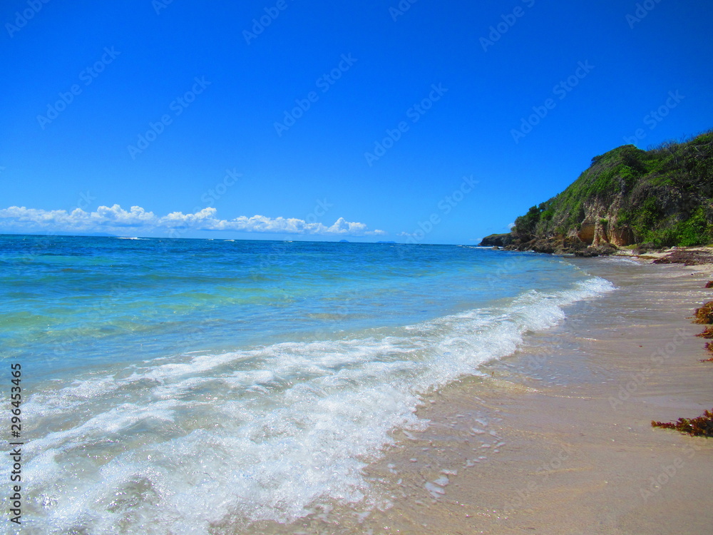 Une longue plage de sable blanc et la mer turquoise sous un ciel sans nuage
