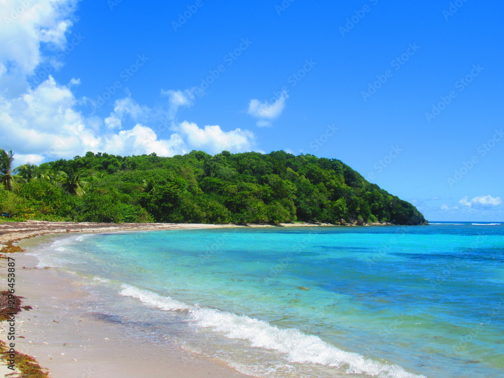 la mer turquoise et une colline entour une plage déserte