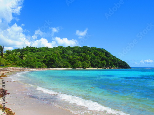 la mer turquoise et une colline entour une plage déserte © Patrick
