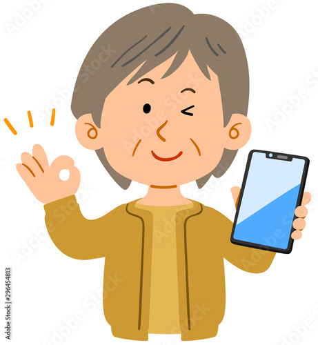 スマートフォンを持ってOKのハンドサインを示すシニアの女性