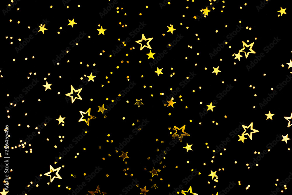 Fototapeta premium Falling star shape confetti on black background. Flat lay, top view. Copy space for your text.