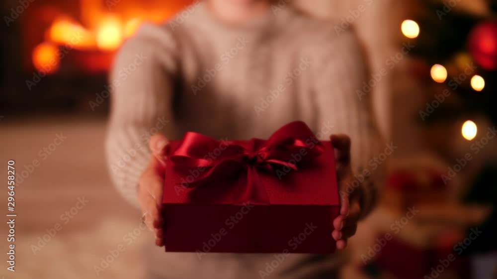 4k video of smiling woman sitting at burning fireplace and CHristmsa tree and showing present box to the camera 4k video of smiling woman sitting at burning fireplace and CHristmsa tree and showing present box to the camera