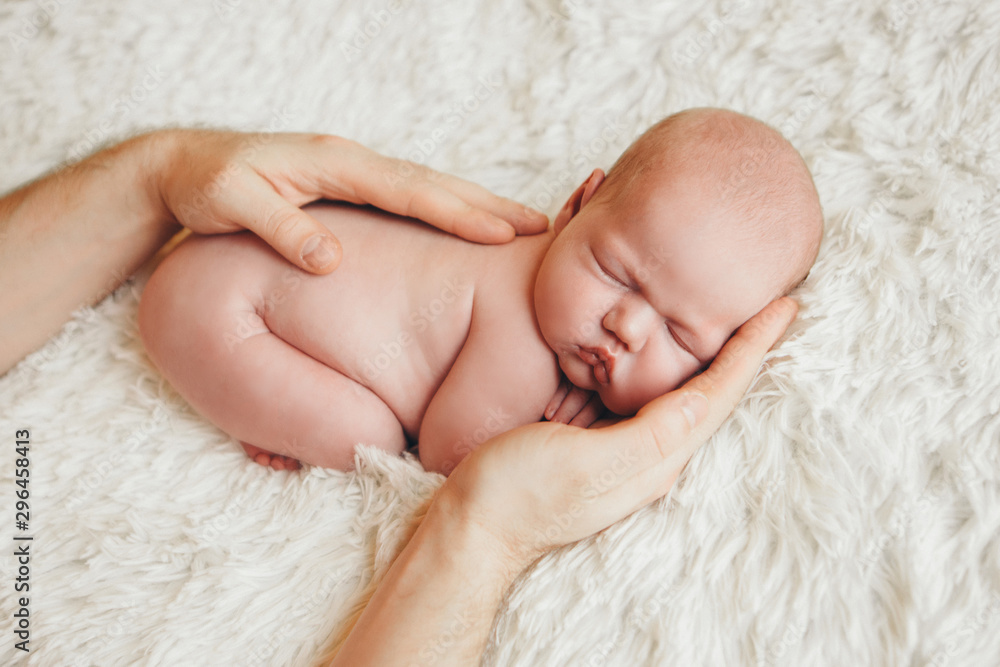 naked newborn baby lying on the hands of parents on a white background. Imitation of a baby in the womb. beautiful little girl sleeping lying on her stomach. naked newborn baby lying on the hands of parents on a white background. Imitation of a baby in the womb. beautiful little girl sleeping lying on her stomach.