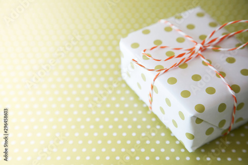 Green gift with ribbon on the green polka dot background