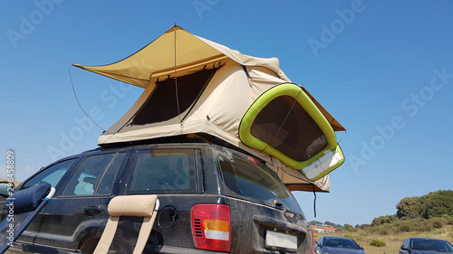 caravan tent on the top of the car by the beach photo